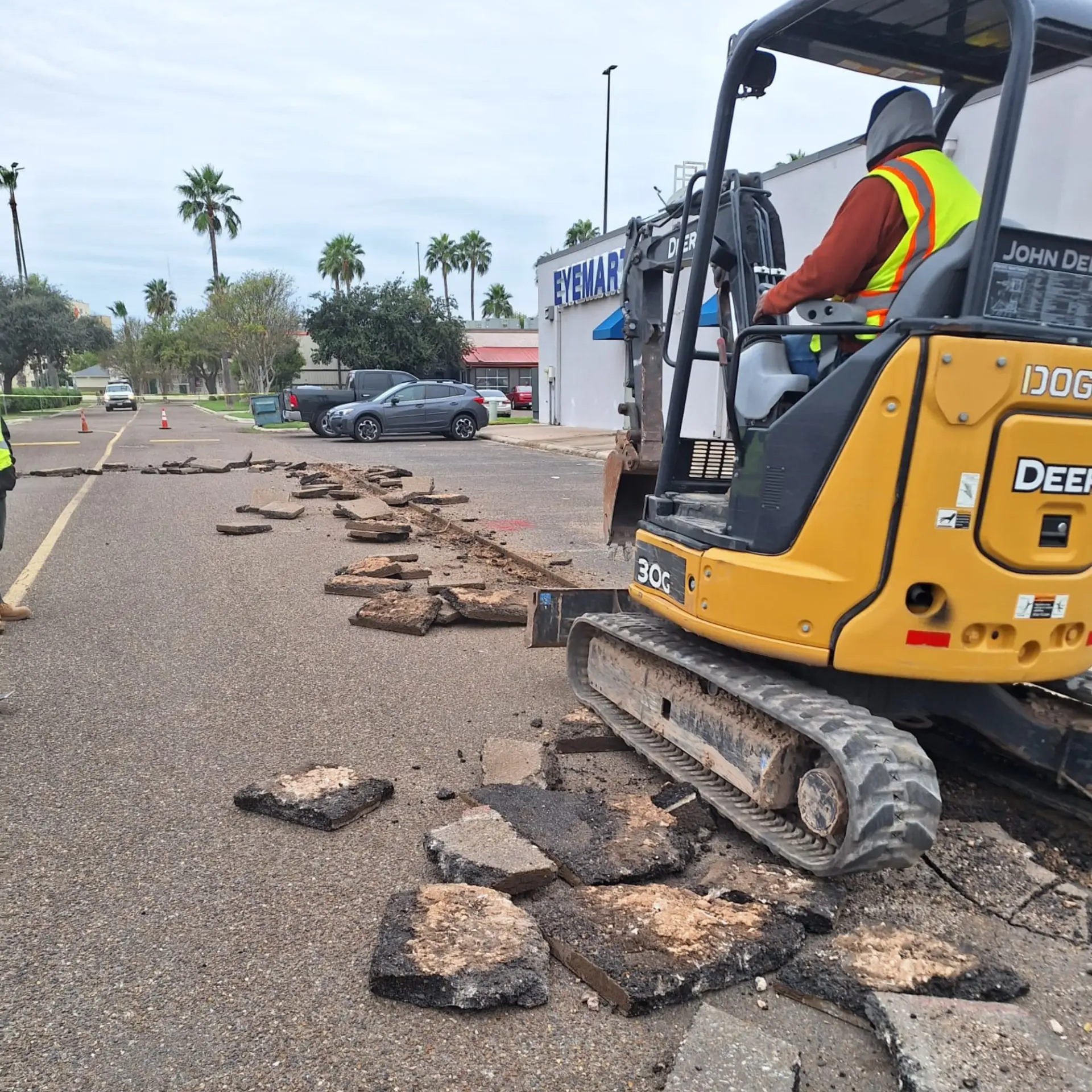 Excavator breaking up asphalt during a site excavation project