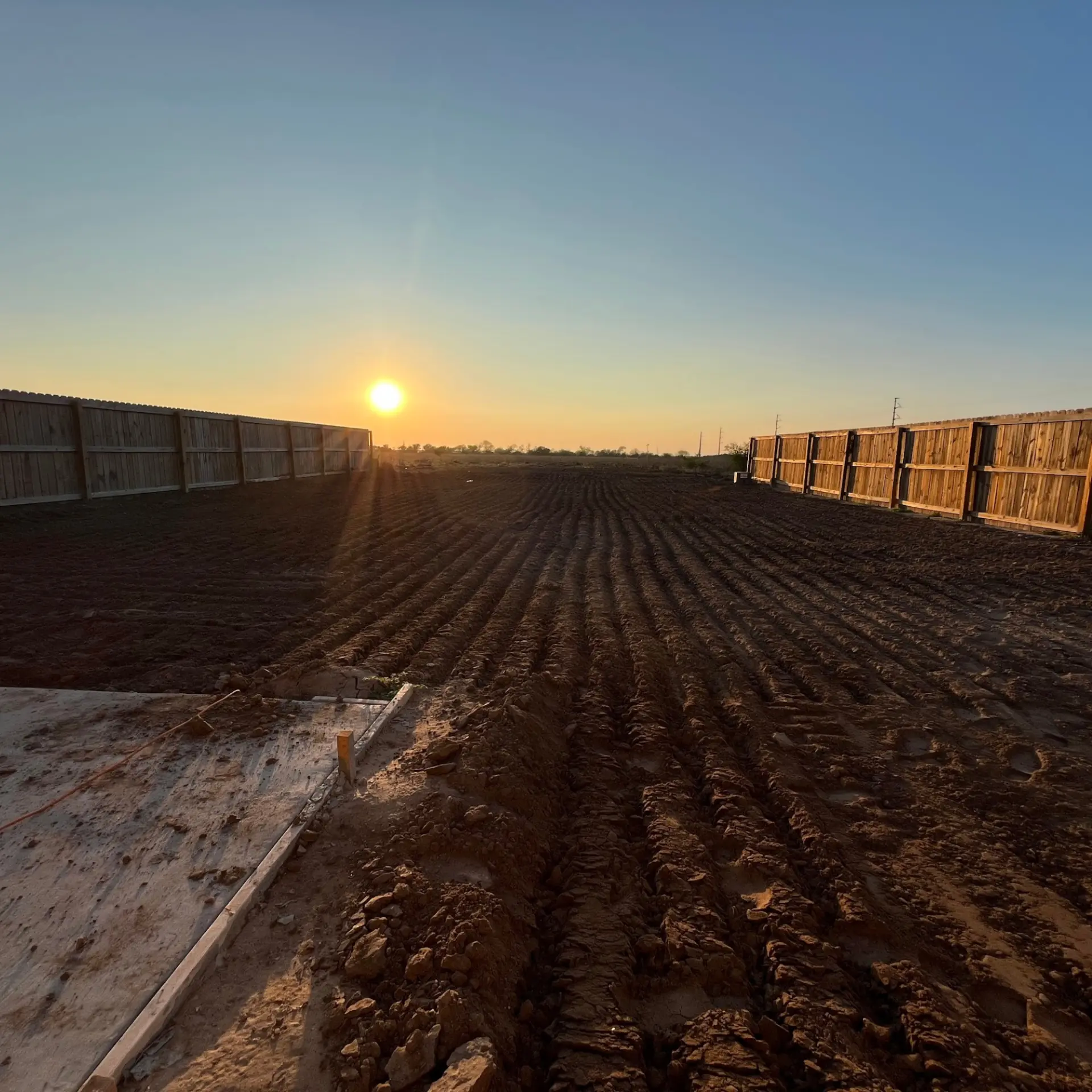 J&J Building Solutions graded and leveled dirt lot at sunset